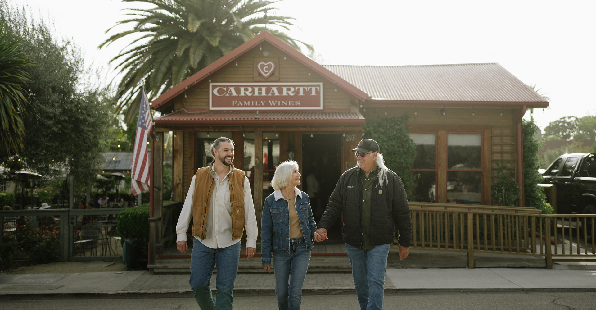 The Carhartt family walking together and smiling in front of the Carhartt Family Wines tasting room in Los Olivos, California.
