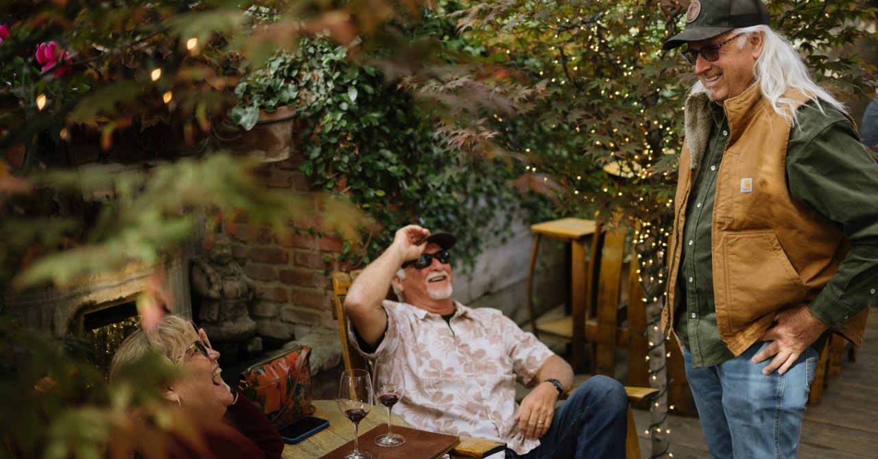 Guests laughing over red wine on the Carhartt Family Wines patio in Los Olivos.