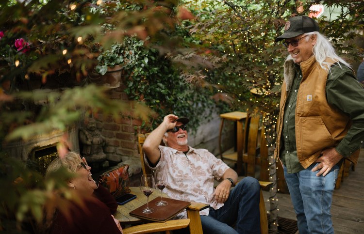 Guests laughing over red wine on the Carhartt Family Wines patio in Los Olivos.